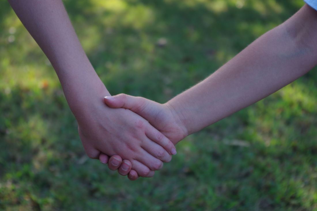 A photo of the hands of two children clasped together.